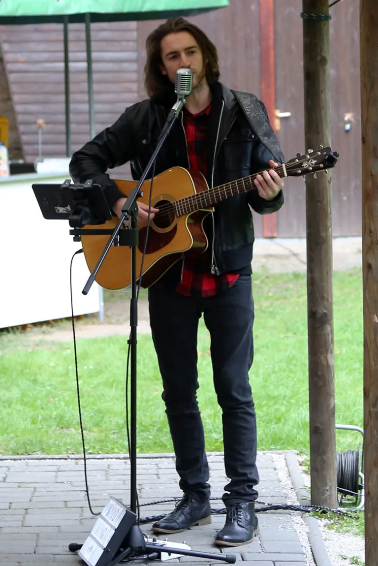 Wladi singt und spielt Gitarre bei einer Veranstaltung im Freien